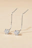 Minimalist silver pull-through threader earrings with solitaire moissanite gem on beige background.