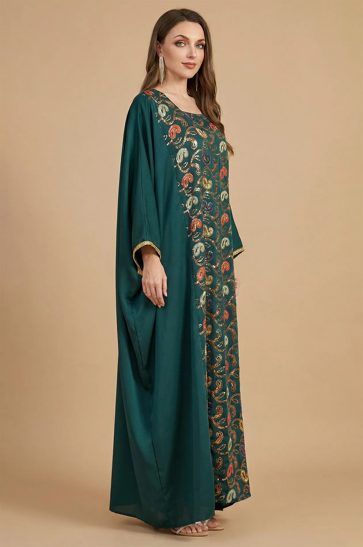 Side profile of the green Amiri Farasha kaftan highlighting the fluid drape and gold-trimmed sleeves.