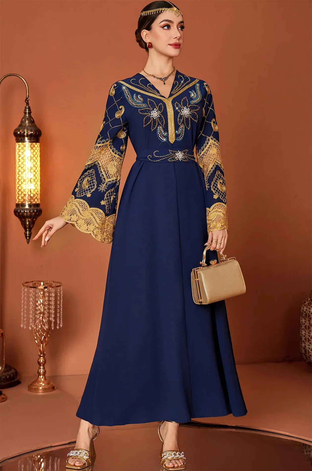 Model posing with the Aysel royal Moroccan kaftan and a gold clutch bag.