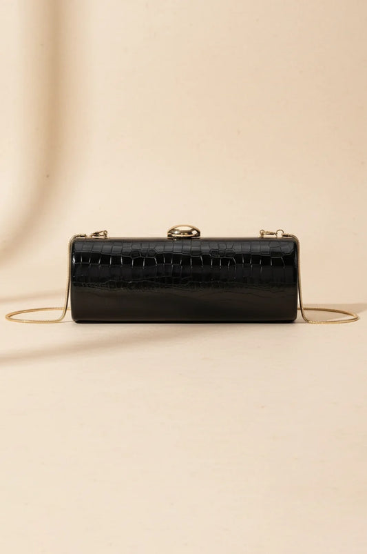 Front view of the black glossy crocodile embossed hard shell cylinder clutch with gold hardware.
