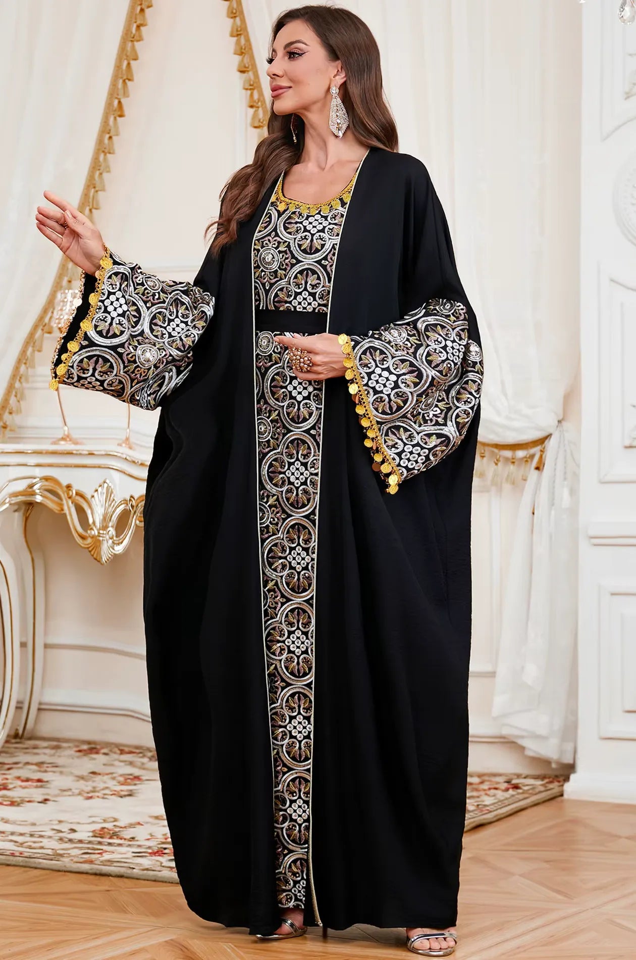 Side lifestyle pose of the Black Novae kaftan showing the movement of the fabric and the decorative gold coin finishes on the sleeves.