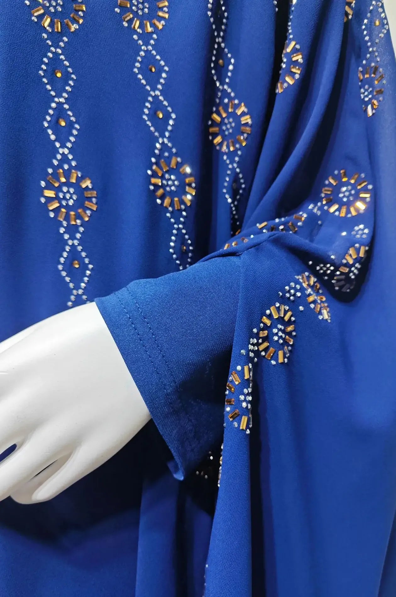 Macro detail of the hand-stitched gold and silver rhinestone embroidery on the sleeve of the Blue Cassia Kaftan.