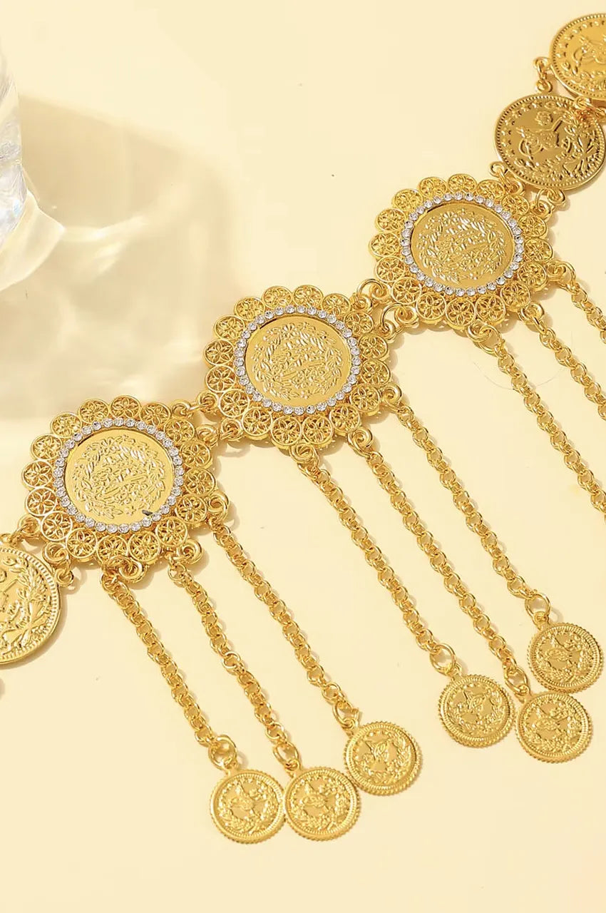 Macro shot of the central gold medallion featuring a coin center and rhinestone border.