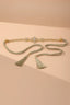 Full view of the Gold Geometric Rhinestone Spike Link Chain Belt with tassel ties on a beige background.