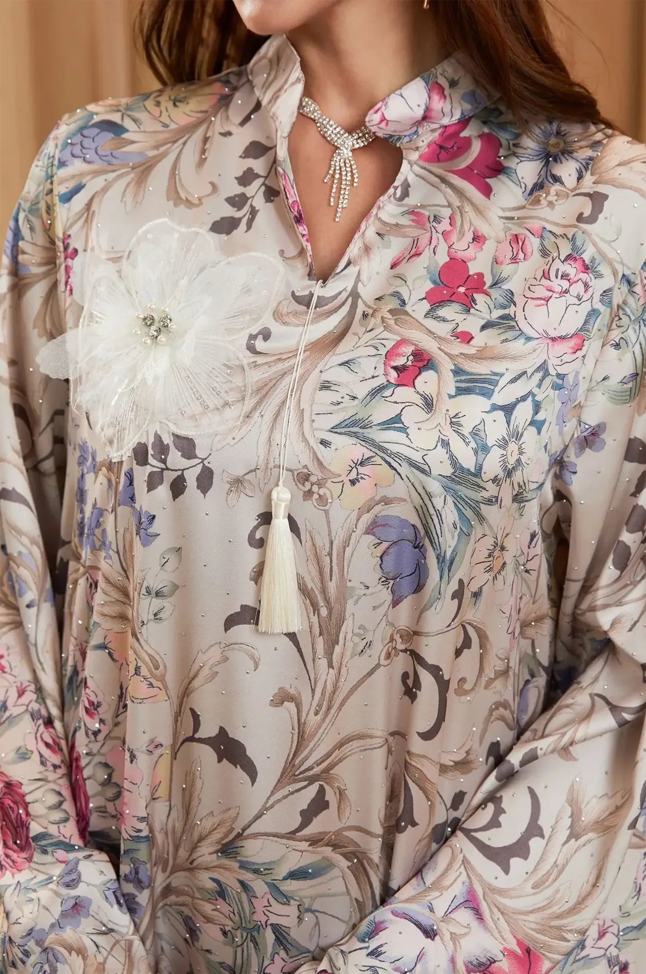 Close-up of the 3D floral appliqué, tassel, and rhinestone details on the Lyris kaftan.
