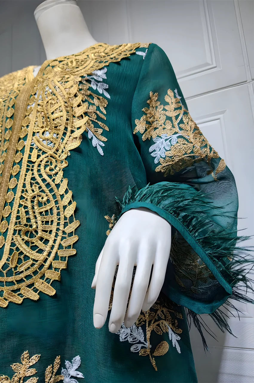 Close-up of Mhaya emerald feather-sleeve kaftan showing feather cuff and gold botanical embroidery.
