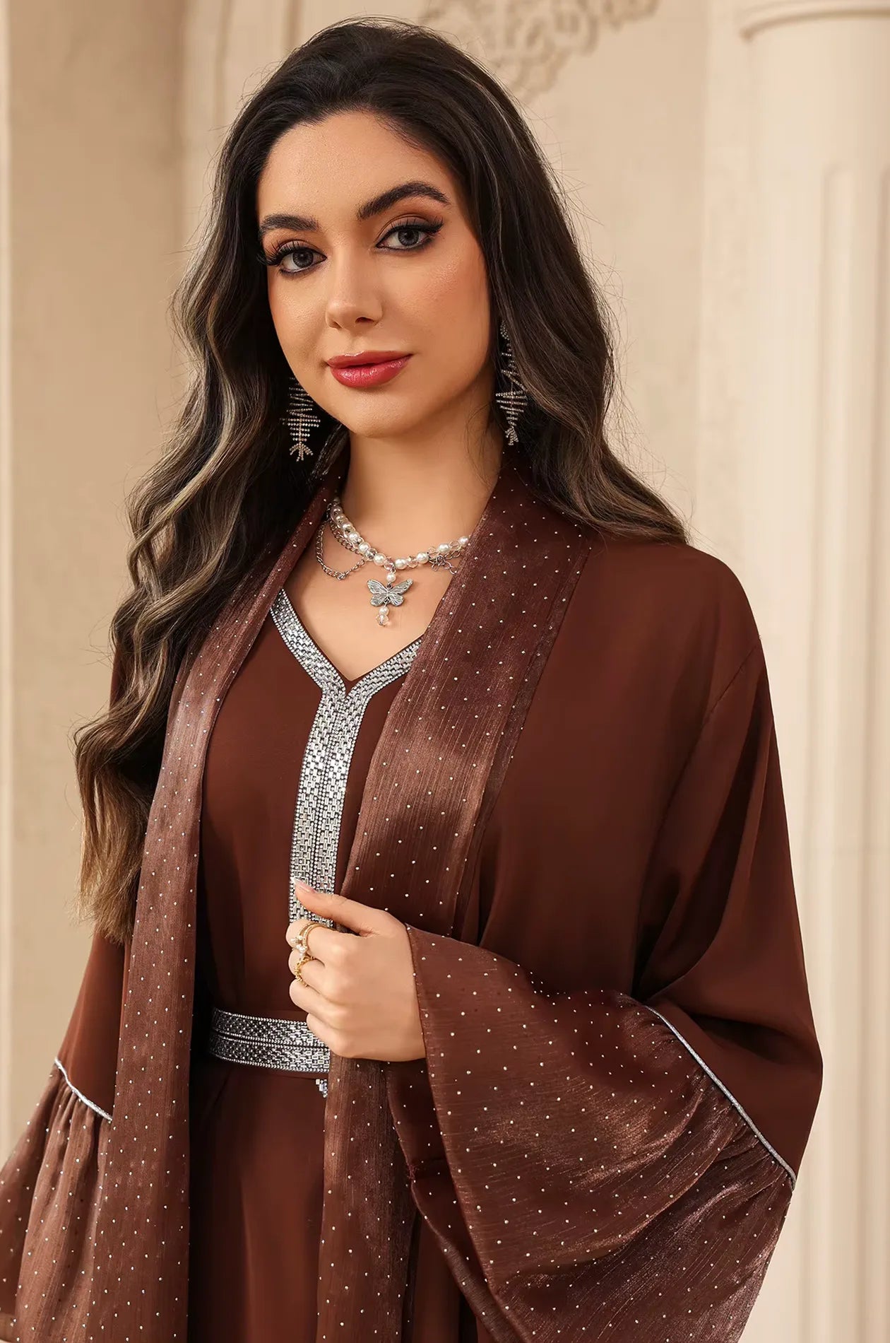 High-fashion portrait of the Auris Brown solid color Kaftan styled with butterfly pendant jewelry and shimmering fabric details.