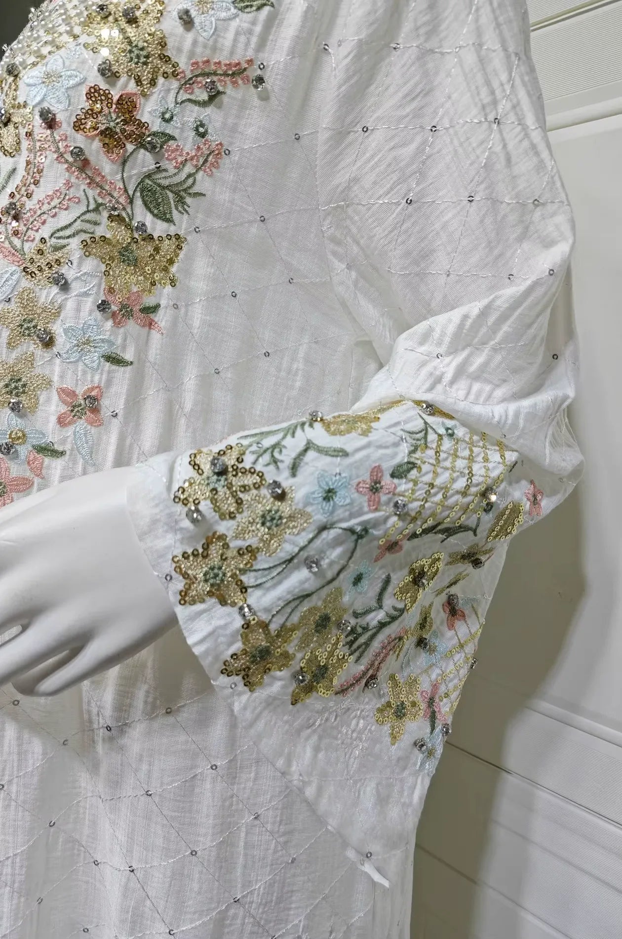 Detailed shot of the floral embroidered bell sleeves on the premium white Equis modest kaftan.