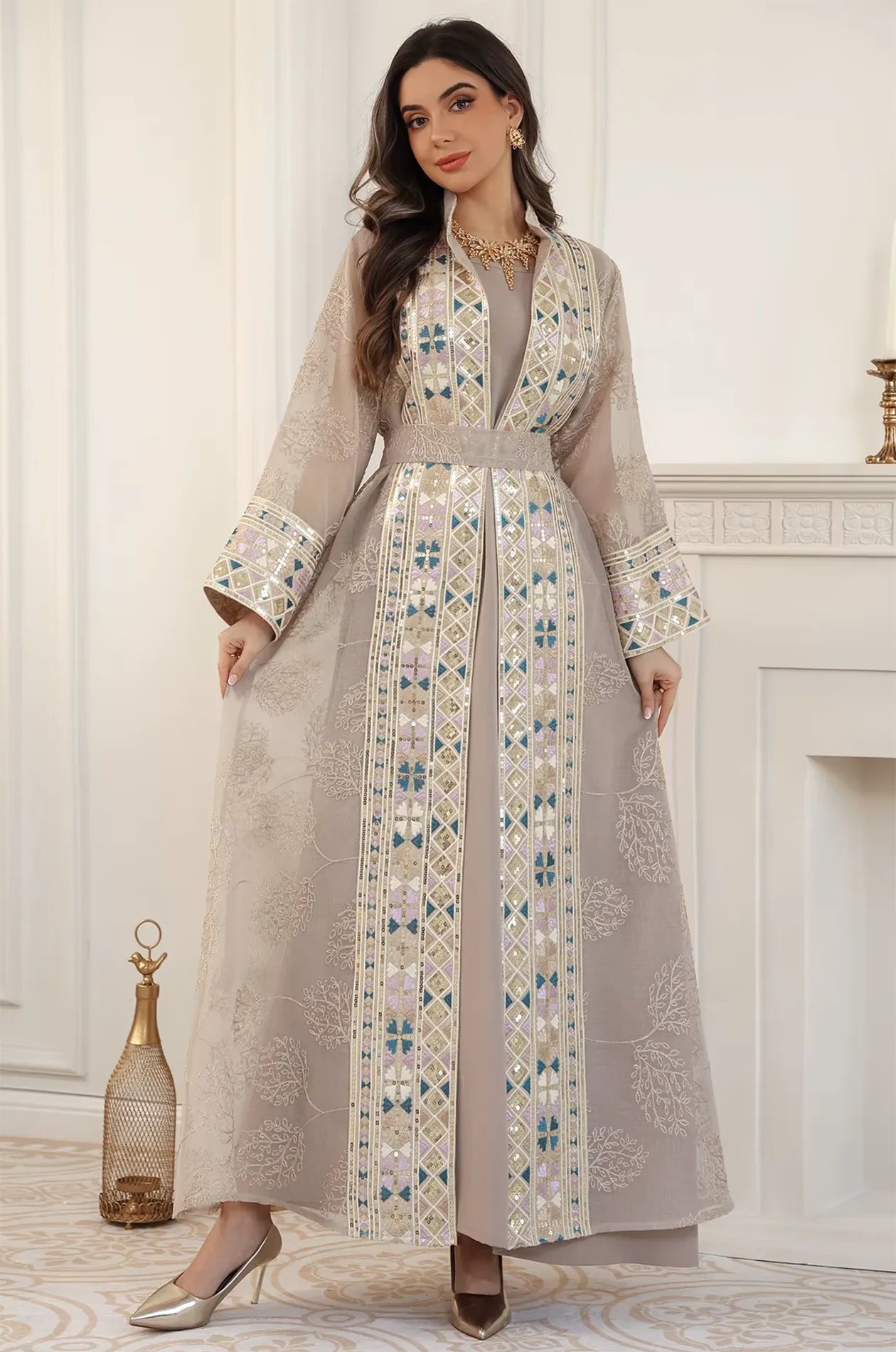 A model posing in the full-length Gienah chic kaftan in apricot beige, emphasizing the elegant drape and craftsmanship.