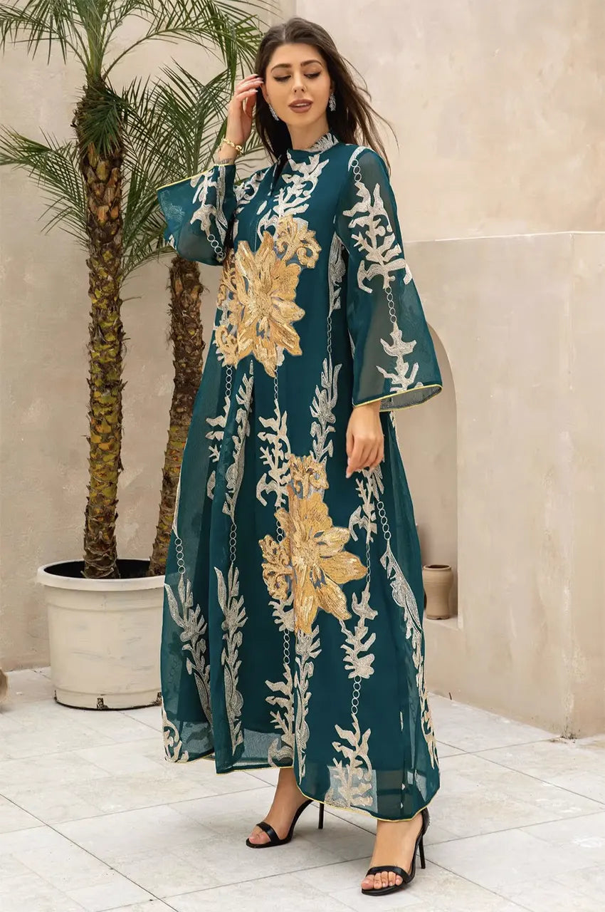 Lifestyle shot of the emerald green Maliya flower kaftan in an outdoor resort setting with palm trees.