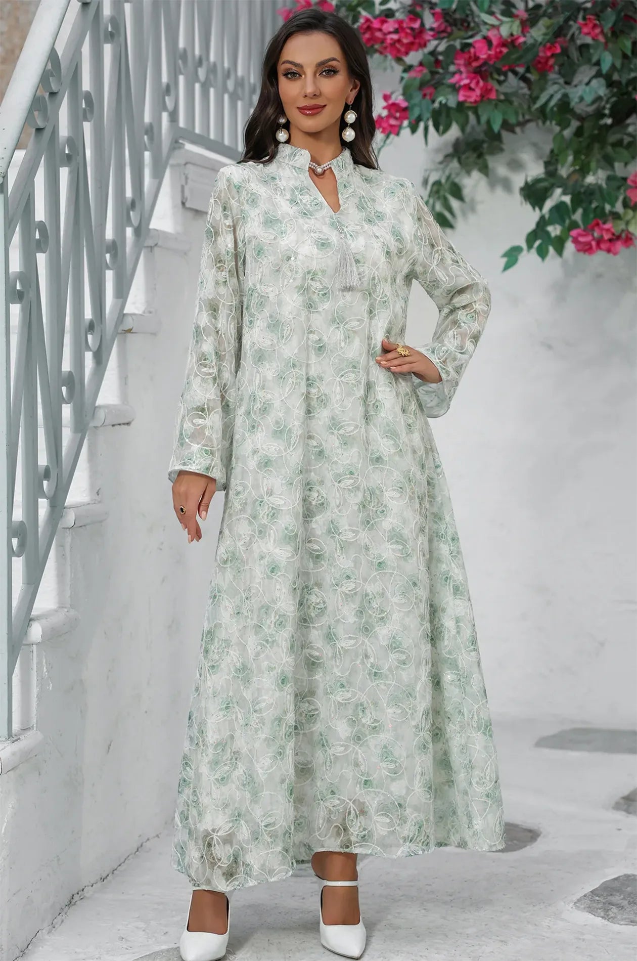 Lifestyle shot of the light green Lyana kaftan near a white staircase.