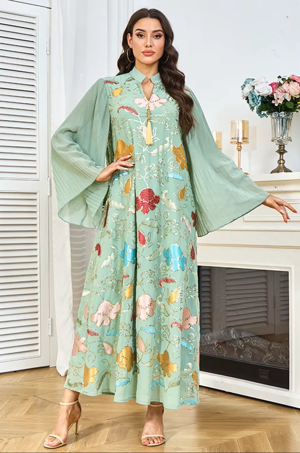 Lifestyle shot of the Marylin Green Tassel Kaftan with pleated butterfly sleeves, styled in a sophisticated home interior.