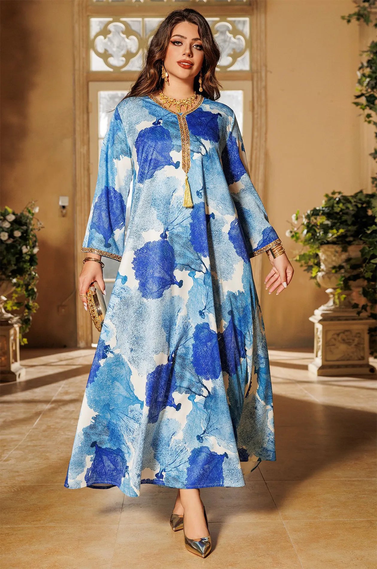 Model walking in the Navae blue tropical print kaftan in a luxury architectural setting.