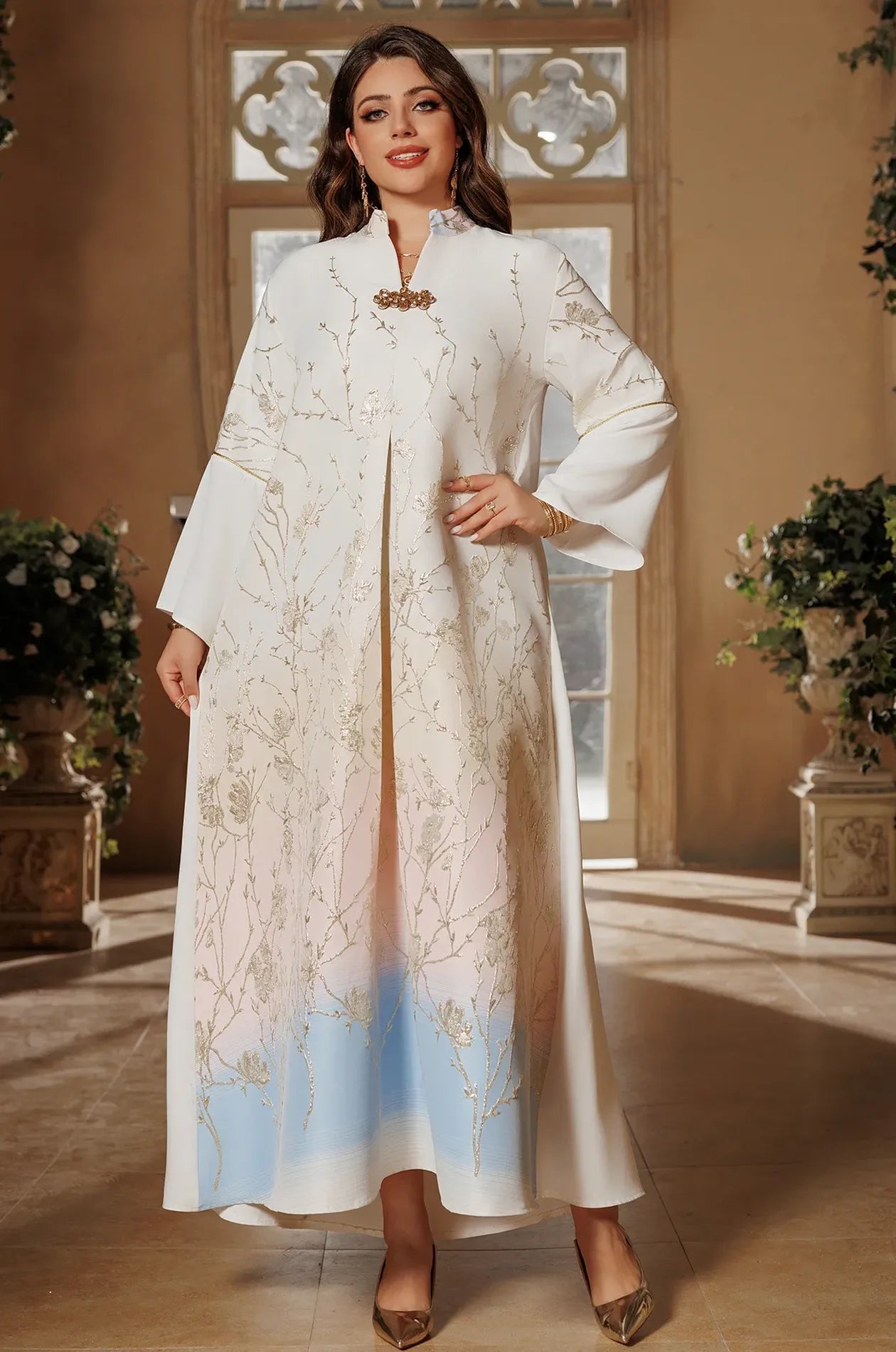 Standing portrait of the Light Blue Tayla Botanical Kaftan with a hand-on-hip pose to emphasize the flowing fabric and gradient color.
