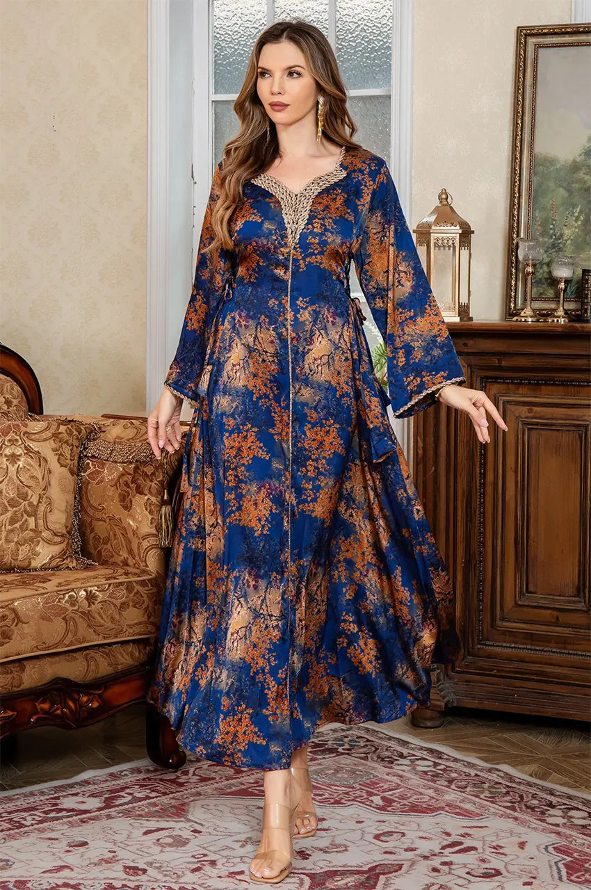 Model standing in an interior setting wearing the Noria blue fitted kaftan with golden floral embroidery.