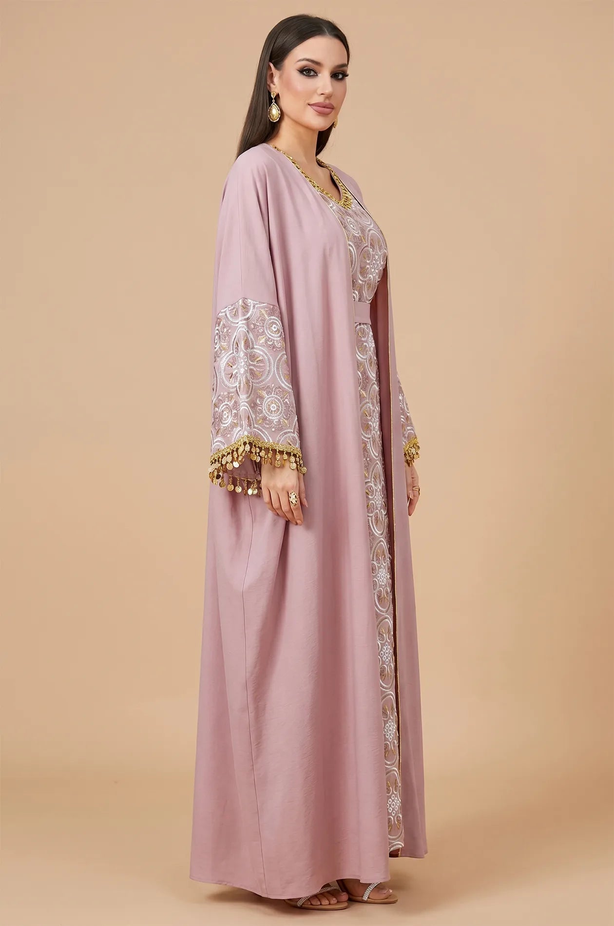 Side profile of the powder pink Novae kaftan highlighting the flared sleeve design and silver embroidery patterns.