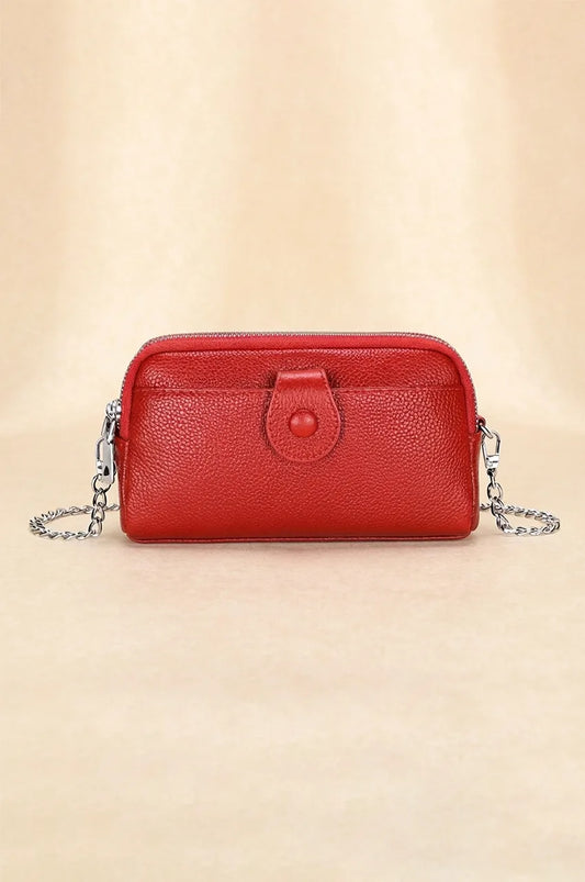 Front view of red pebbled leather crossbody phone bag with front snap pocket and silver chain strap.