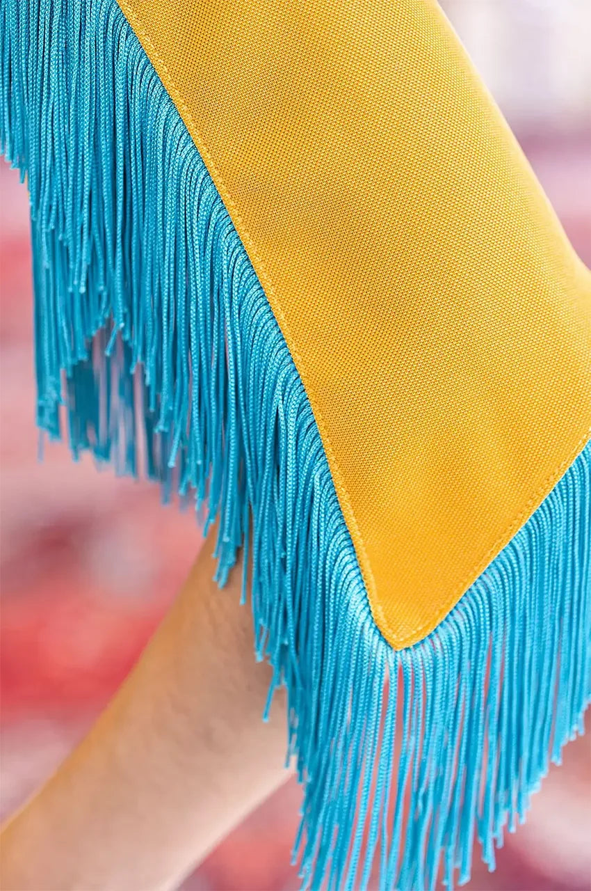 Close-up macro shot of the turquoise fringe trim on the Zayna kaftan cape sleeve.