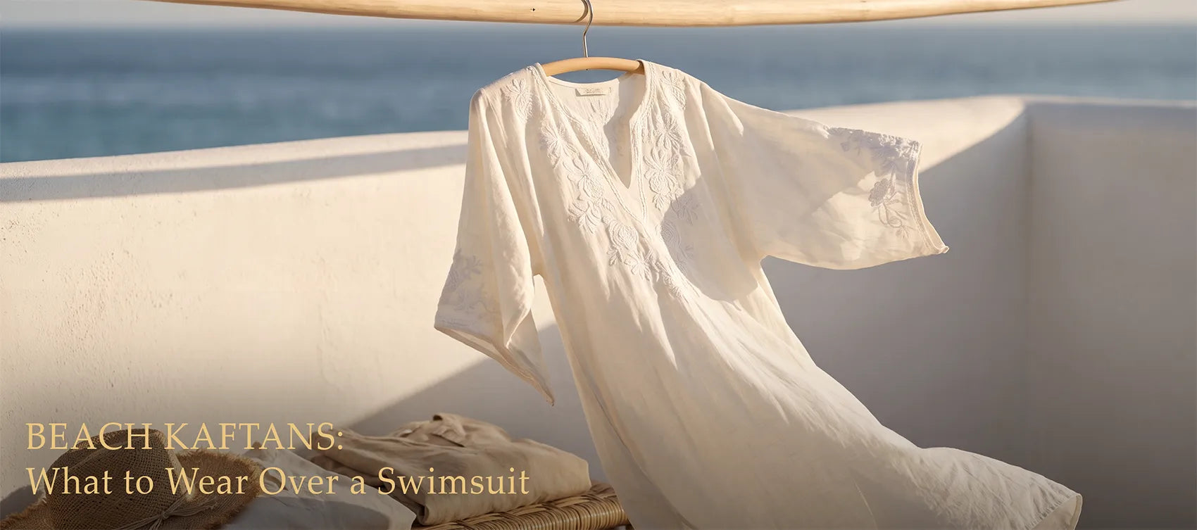 White embroidered cotton beach kaftan on a hanger above the sea — Beach Kaftans: What to Wear Over a Swimsuit