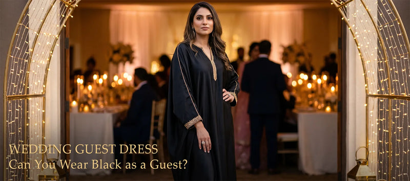 Woman wearing a floor-length black kaftan with gold trim standing at the entrance of a candlelit wedding reception