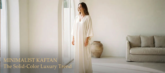 Woman wearing a floor-length ivory minimalist kaftan in a bright white minimalist interior