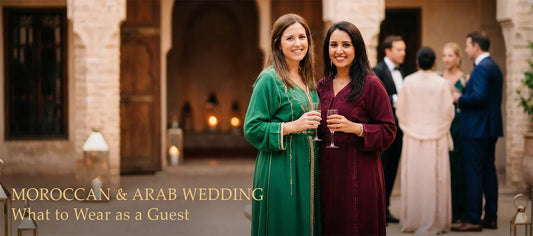 Two women wearing floor-length kaftans in emerald green and burgundy at a Moroccan wedding reception