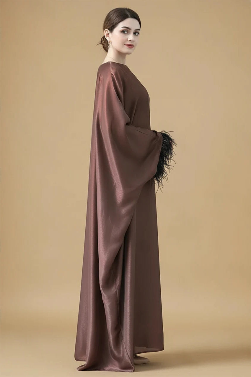 Side view of ALARA brown satin kaftan gown with flowing draped sleeves and black feather trim