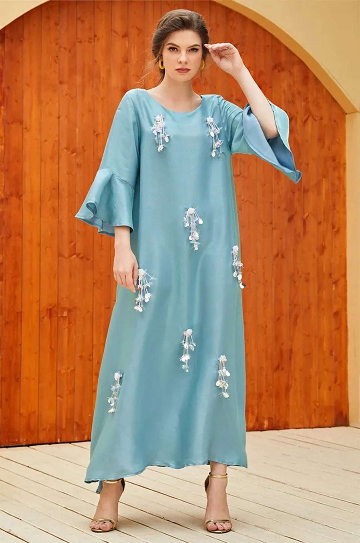 Full-length shot of the Alima aqua blue kaftan with gold heels.