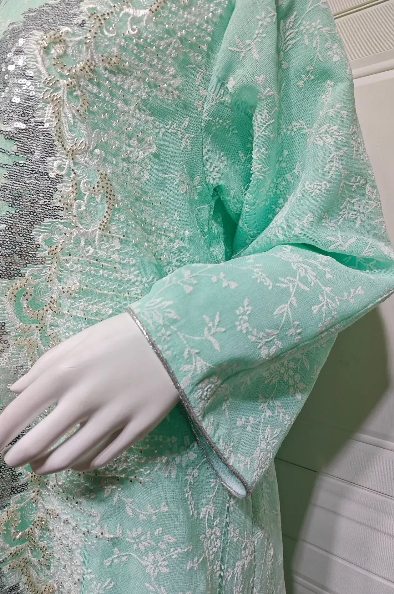 Close-up detail of the sleeve and silver floral embroidery on the Alura Shimmer Kaftan in gray.