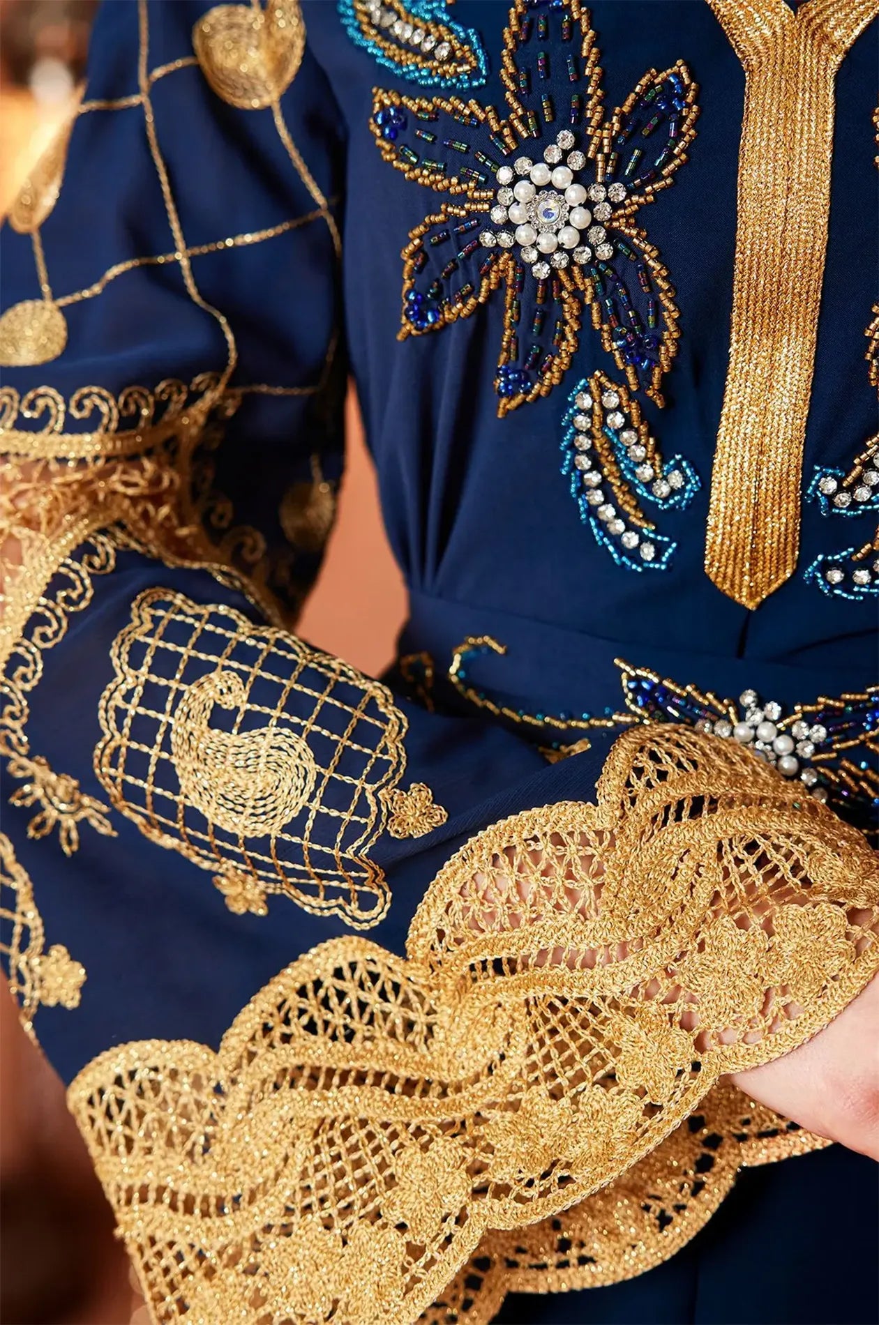 Close-up detail of the gold floral beads, pearls, and lace on the Aysel kaftan.