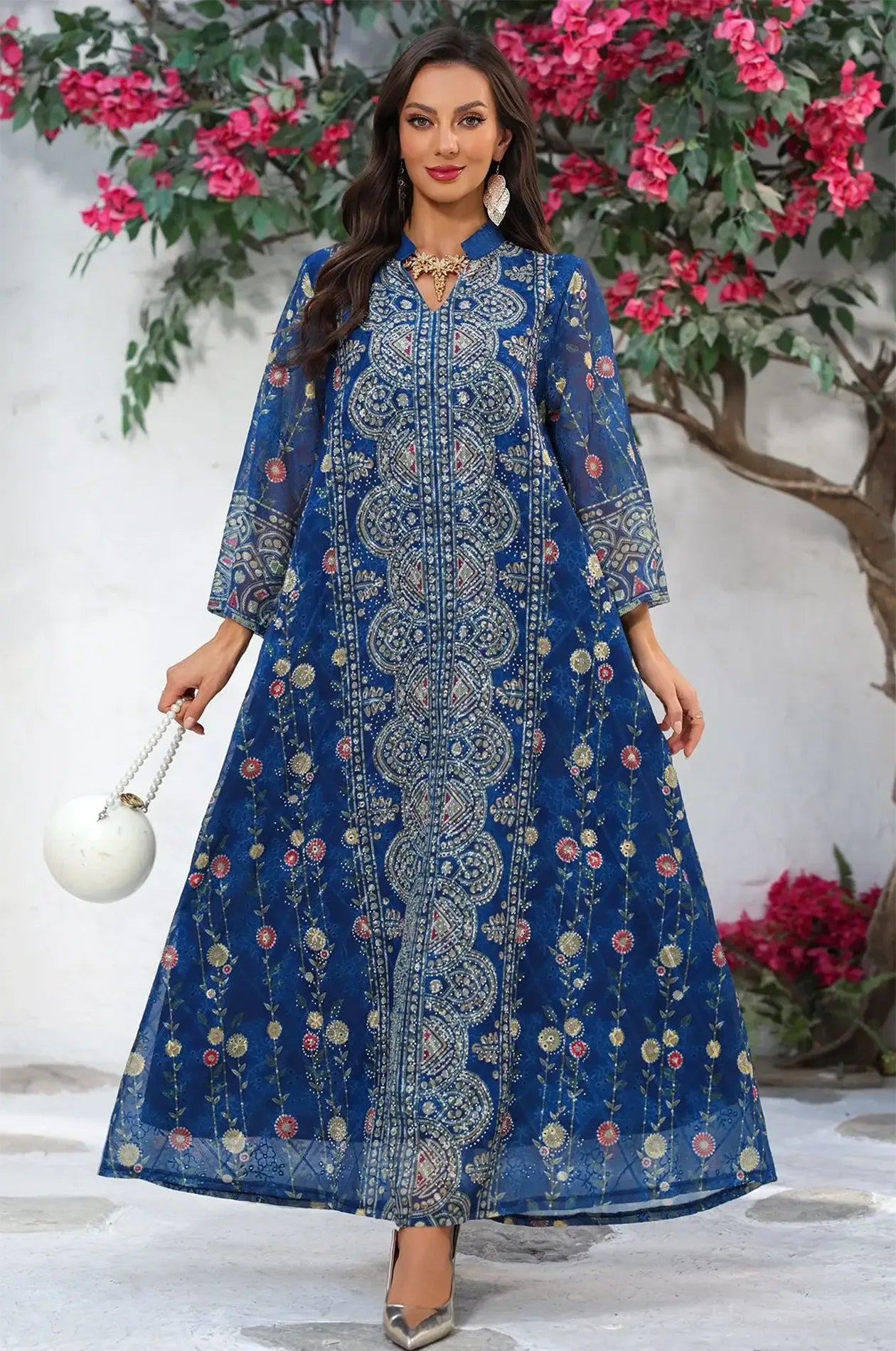 Full-length shot of the Azari navy chiffon kaftan maxi dress in a garden setting with vibrant floral accents.