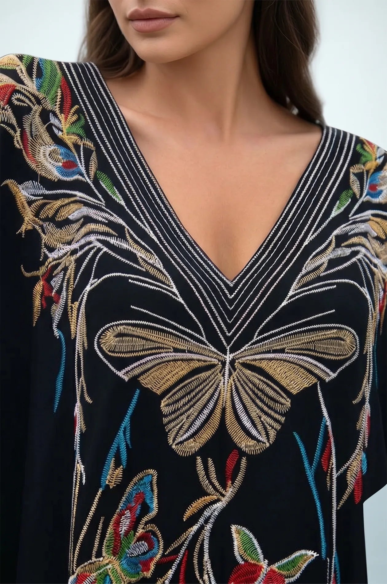 Close-up of black kaftan striped V-neckline and butterfly embroidery