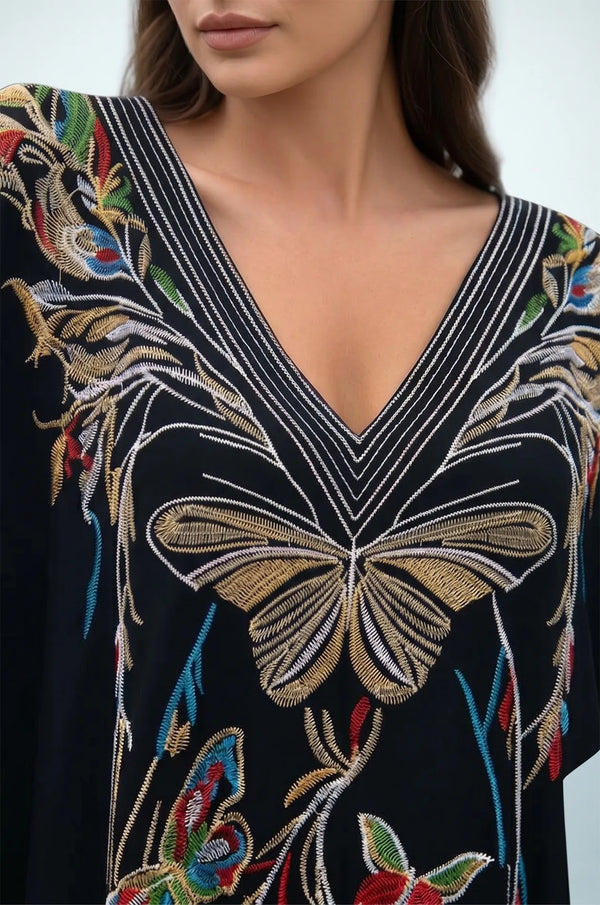 Close-up of black kaftan striped V-neckline and butterfly embroidery