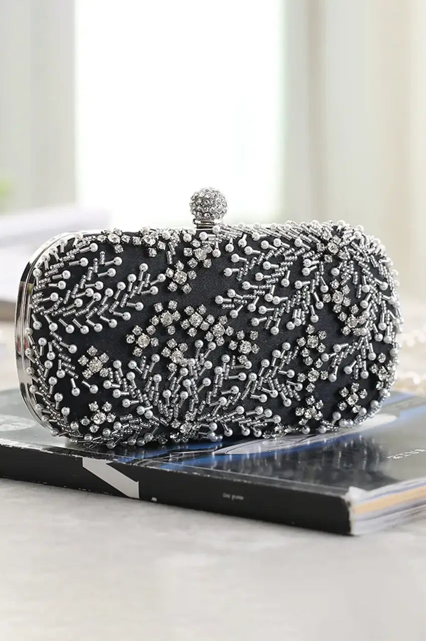 Side profile of black luxury evening bag showing the 3D texture of silver beads and crystals on black satin.
