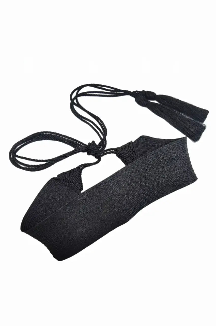 Artistic flat lay of the black sash belt showing the braided ropes and tassels.