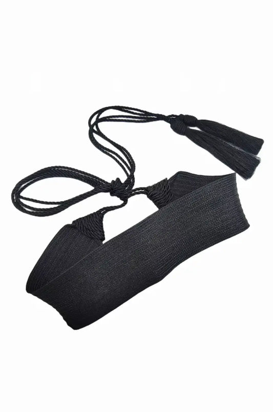 Artistic flat lay of the black sash belt showing the braided ropes and tassels.