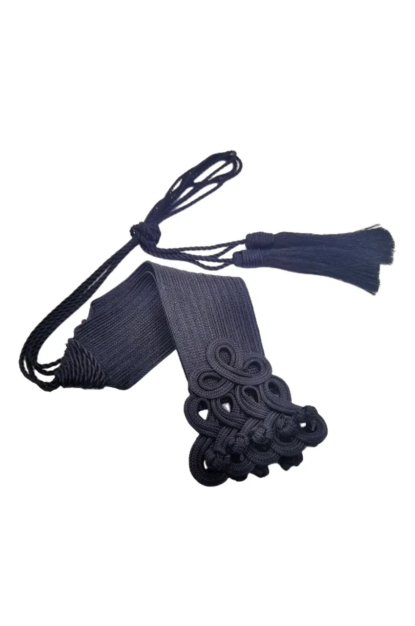 Folded black cord sash belt showing the long rope ties and tassel fringe.