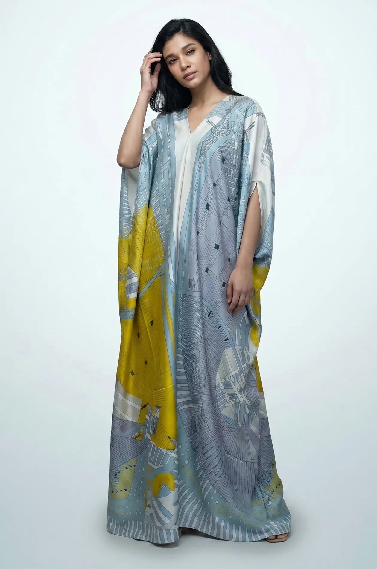 Blue boho beach kaftan with model adjusting hair showing fluid silk maxi
