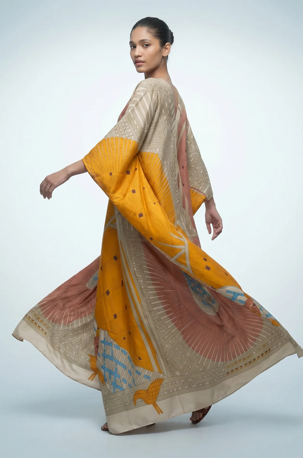 Woman twirling in green silk kaftan with kimono sleeves and bird print