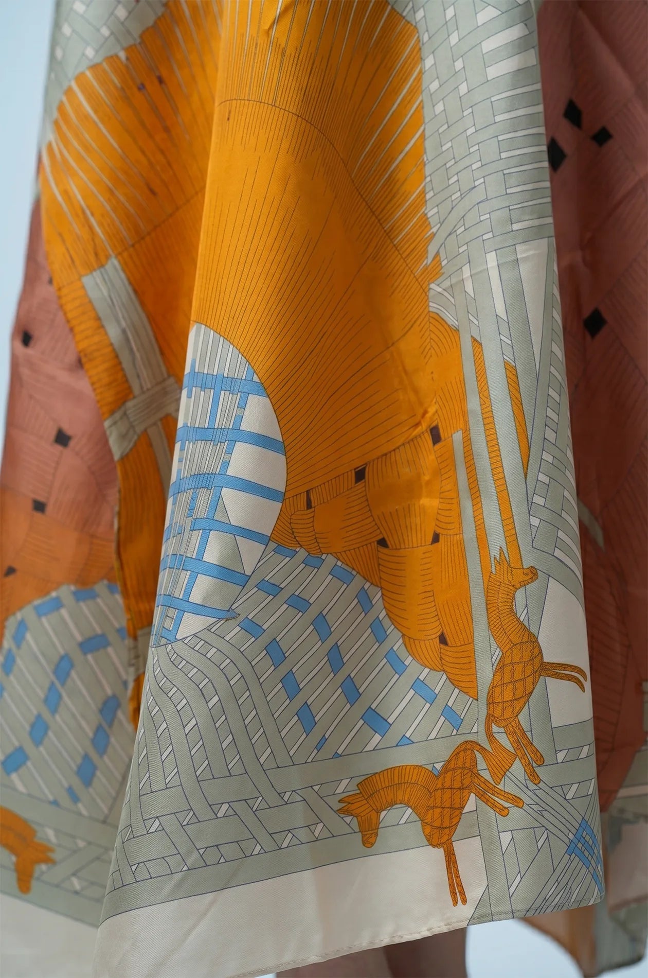 Hem detail of green silk kaftan with mustard terracotta print and animal motifs