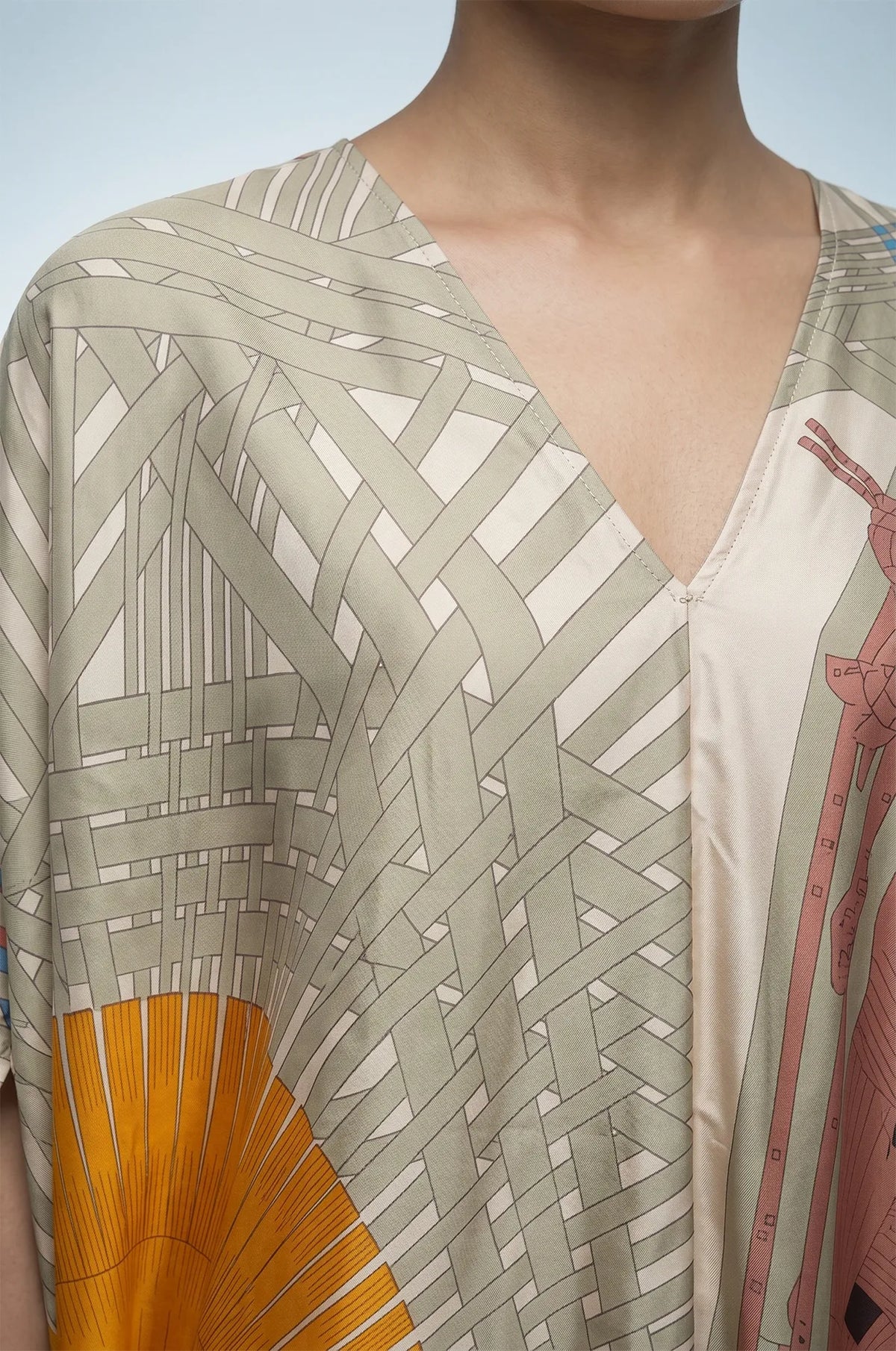 Close-up of green silk kaftan V-neckline and woven basket print detail