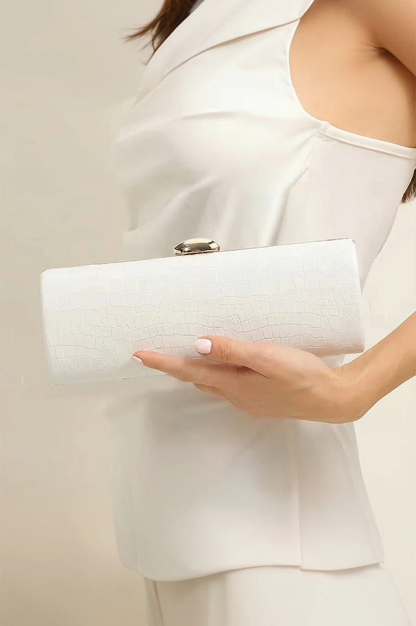 Woman holding a sleek white crocodile patent cylinder clutch, perfect for bridal or summer evening wear.