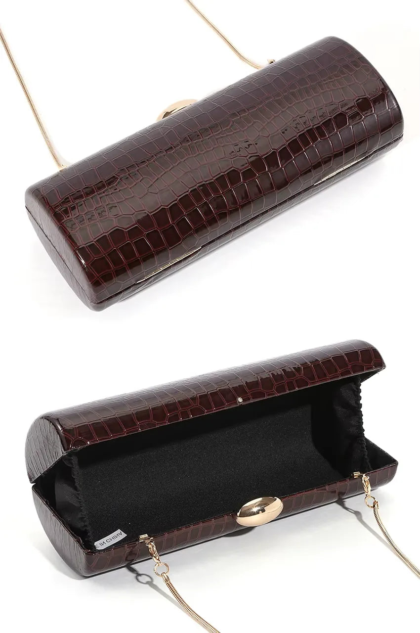 Open view of the burgundy hard case clutch revealing black fabric lining and detachable gold chain strap.