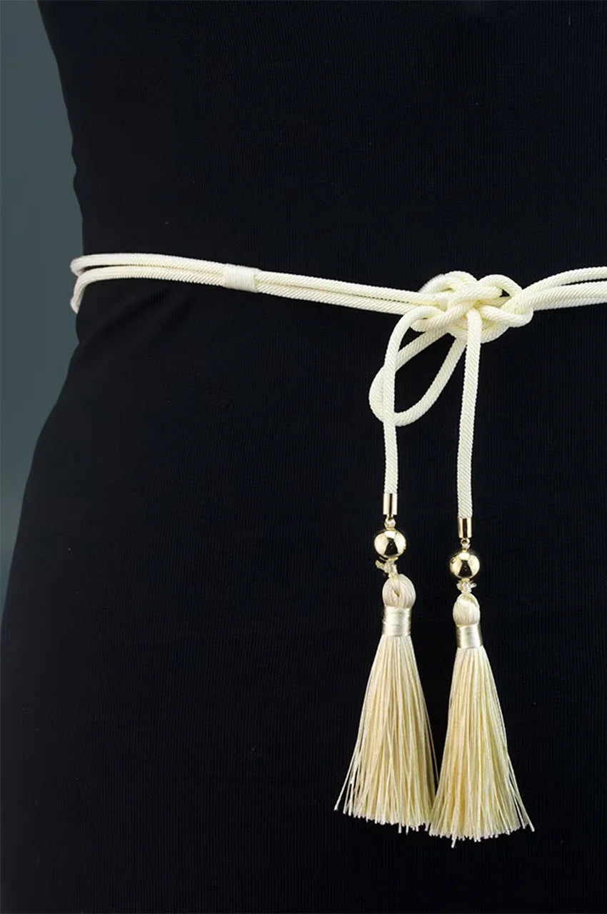 Detail shot of the back closure showing the cream braided rope knotted with hanging tassels.