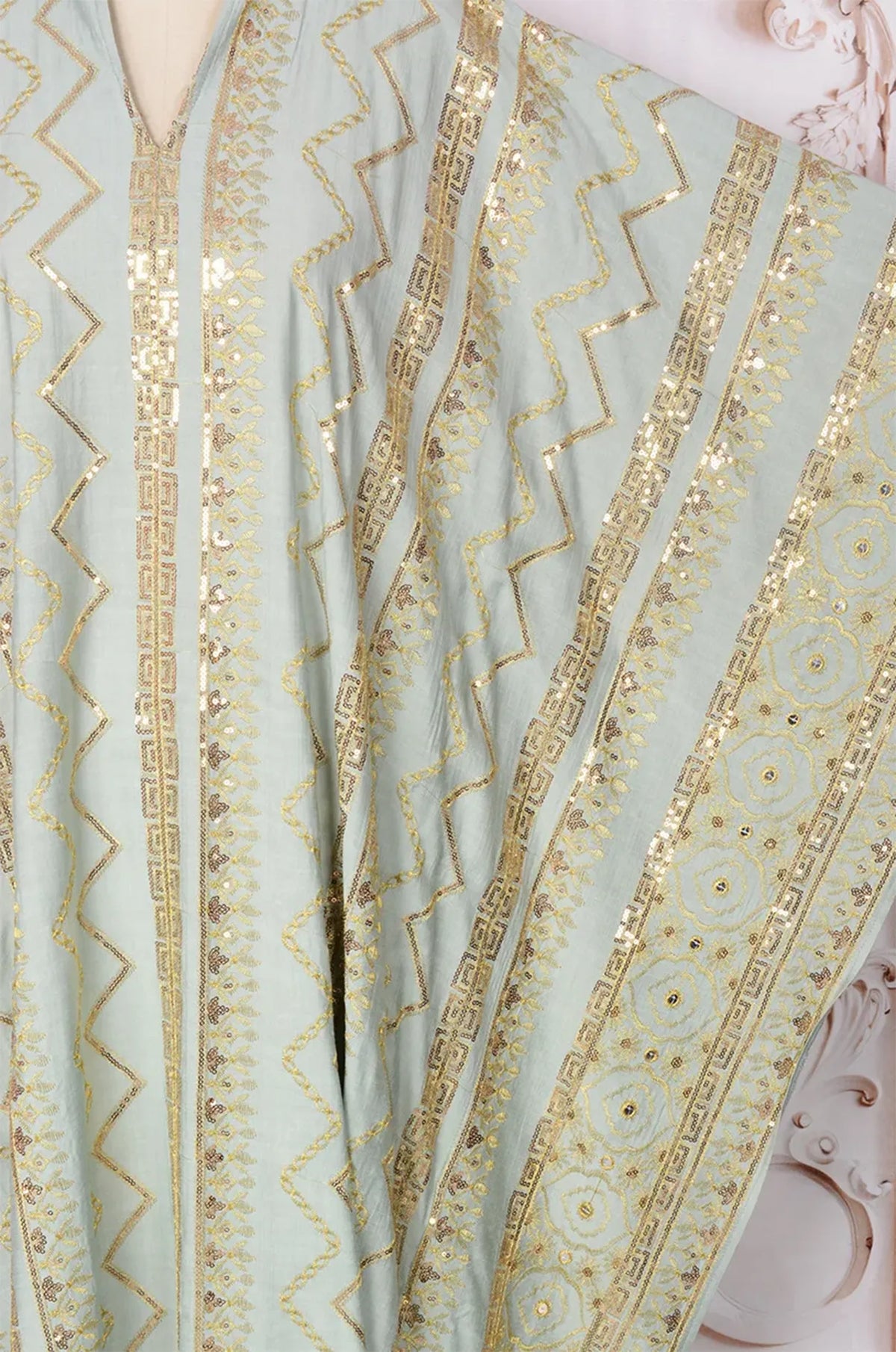Close-up detail of the gold sequin zigzag embroidery on the light green Delphin kaftan.