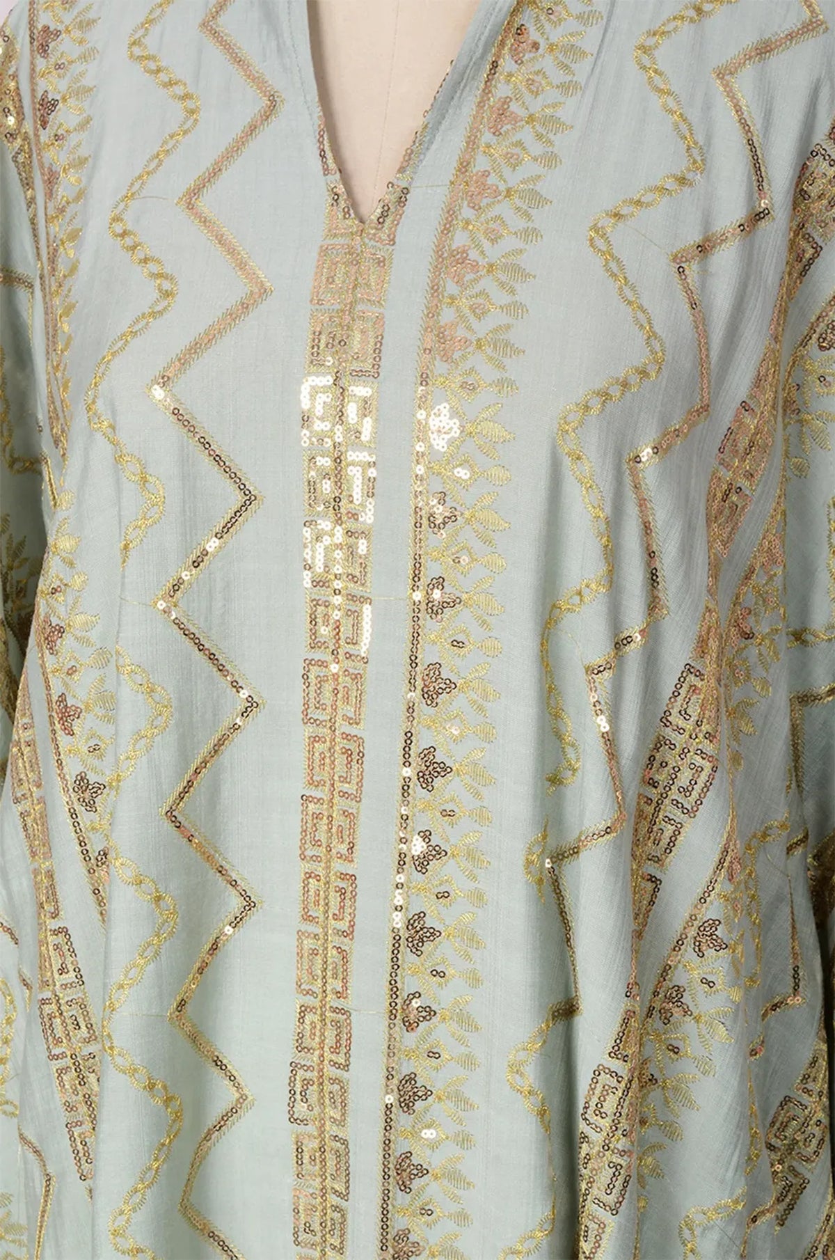 Detailed view of the V-neck collar and gold patterns on the light green Delphin kaftan.
