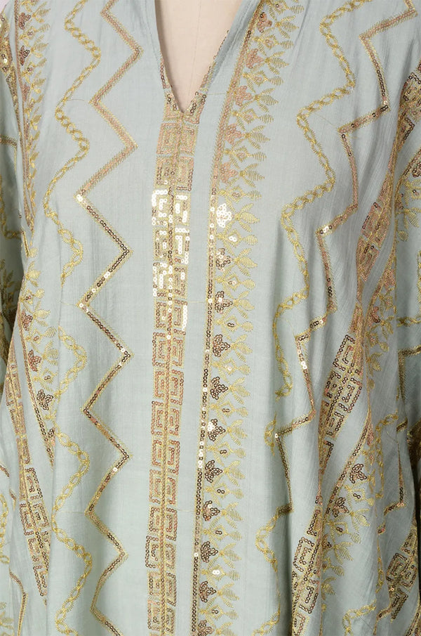 Detailed view of the V-neck collar and gold patterns on the light green Delphin kaftan.