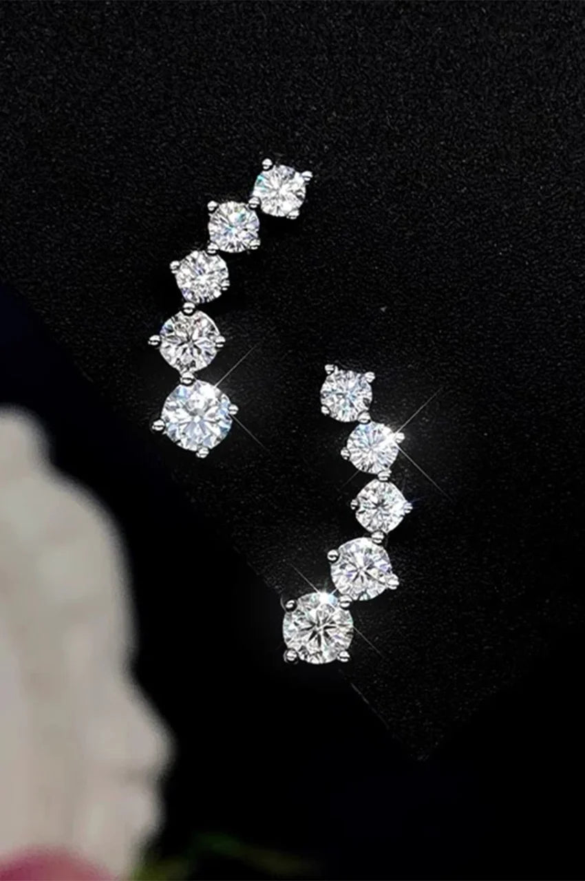 Flat lay of graduated stone ear sweep earrings on black velvet.