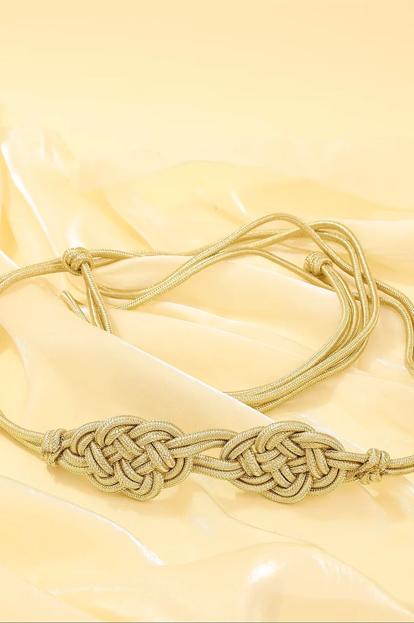 Angled shot of gold cord belt highlighting the dual Celtic knot design and woven texture.