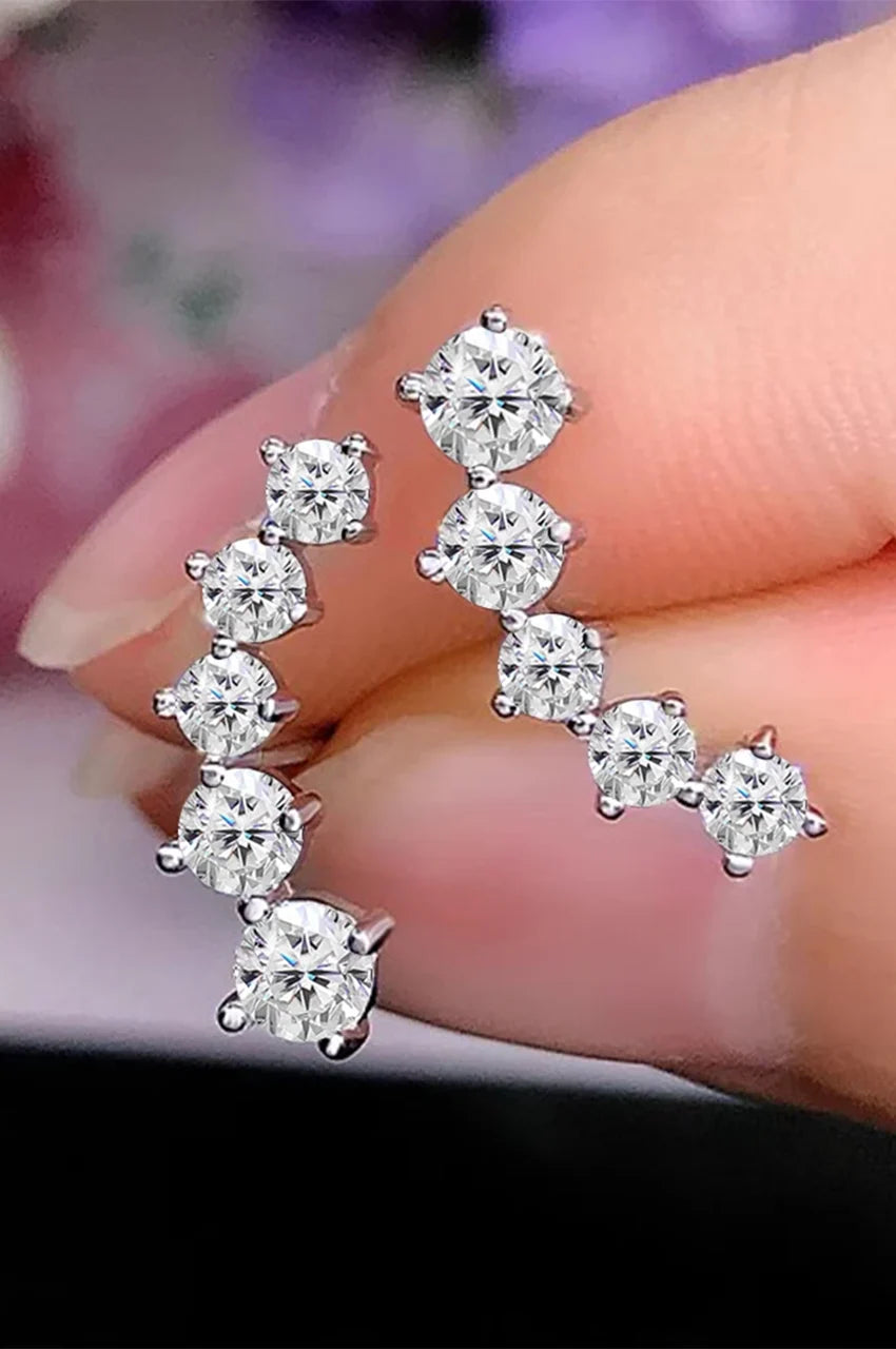 Hand holding a pair of silver ear climbers to show scale and stone brilliance.